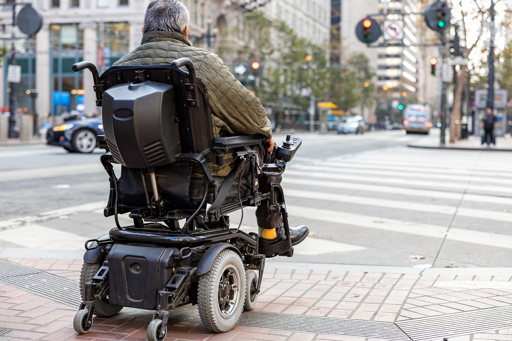 Aan inclusieve openbare ruimte wordt gedacht. Man in elektrische rolstoel op straat
